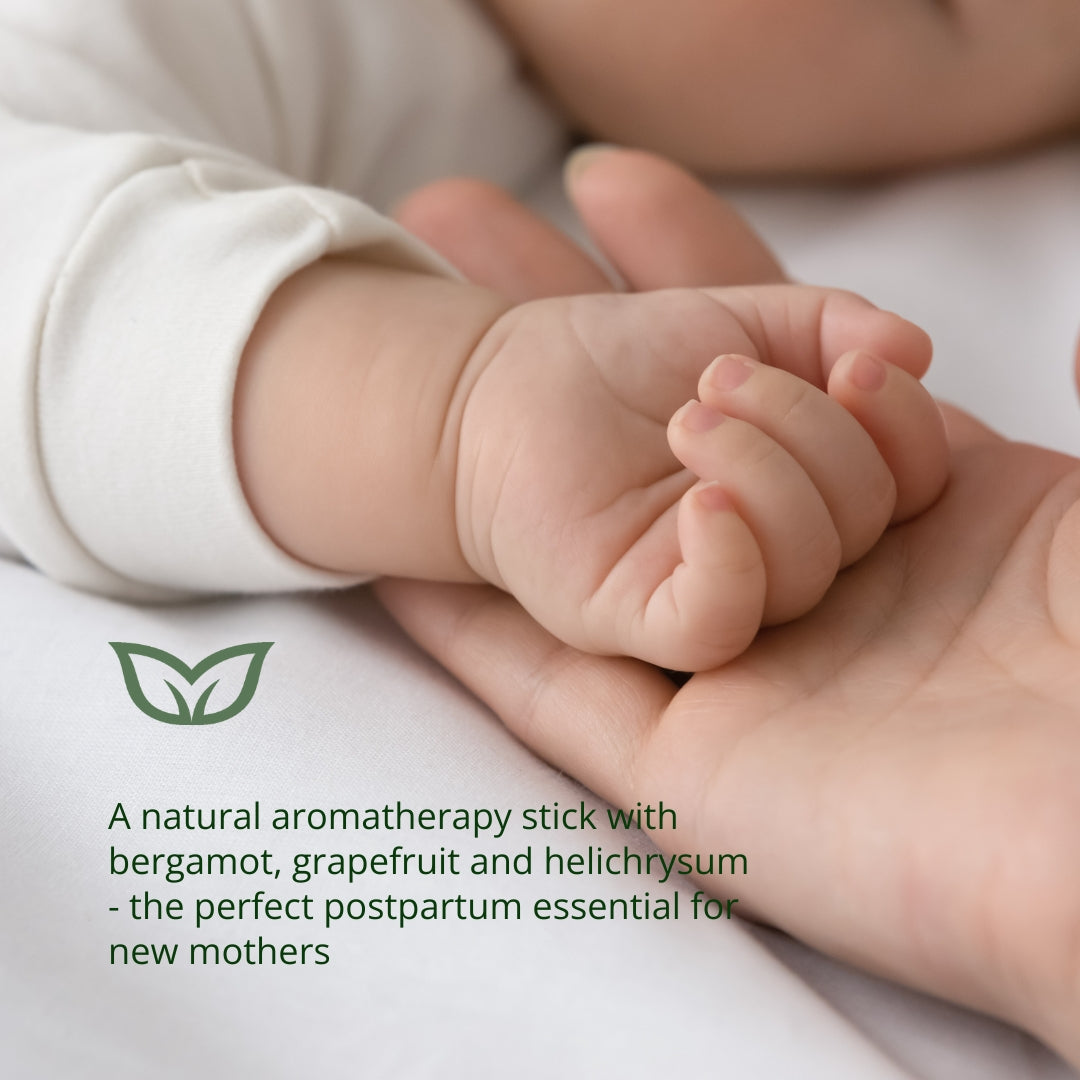 New mother holding baby with natural aromatherapy stick containing bergamot, grapefruit and helichrysum - the perfect postpartum essential oil blend for new mothers&#39; emotional wellness and energy support